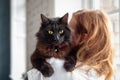 Cute domestic with yellow eyes black cat sitting on woman`s shoulder Royalty Free Stock Photo