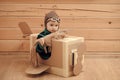 Cute dreamer boy playing with a cardboard airplane. Royalty Free Stock Photo