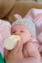 Newborn baby with knit bunny ear hat getting a bottle of milk Royalty Free Stock Photo