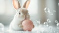 Cute Easter bunny holding a pink speckled Easter egg while surrounded by bubbles and water drops in spa salon. Easter Royalty Free Stock Photo