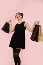 Vulgar, overly happy girl with shopping bags over pink background