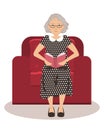 Cute elderly lady is sitting in a red armchair and reading a book