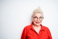 Cute elderly woman in a red shirt with blond short hair wearing glasses looking at the camera Royalty Free Stock Photo
