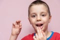 Cute elementary age boy is pulled his baby tooth with hand himself. Royalty Free Stock Photo