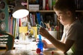 Cute elementary school boy looking into microscope at his desk at home. Young scientist making experiments in his home laboratory Royalty Free Stock Photo