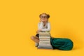 Cute Elementary School Girl Sitting At Books Stack Over Yelow Background Royalty Free Stock Photo