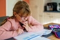 Cute elementary school girl writing in her workbook and doing school homework. Focused child learning and studying indoors Royalty Free Stock Photo
