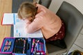 Cute elementary school girl writing in her workbook and doing school homework. Focused child learning and studying indoors Royalty Free Stock Photo