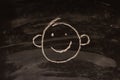 Cute emoji with protruding ears drawn with chalk on a dark chalkboard.