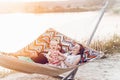 Cute, emotional baby girl in pretty dress with her mother and father in a hammock on vacation, funny baby face at sunset lake Royalty Free Stock Photo