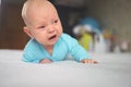 Cute emotional funny newborn infant crying boy laying on bed. Infant baby facial expressions Royalty Free Stock Photo