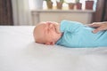 Cute emotional funny newborn infant crying boy laying on bed. Infant baby facial expressions Royalty Free Stock Photo