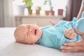 Cute emotional funny newborn infant crying boy laying on bed. Infant baby facial expressions Royalty Free Stock Photo