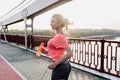 Cute european lady running in morning. Outdoor photo of attractive shapely woman holding bottle of