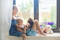 Cute european toddler sisters playing on sill near window