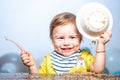 Cute excited funny baby with plate and spoon, babies eating. Kid boy eating healthy food. Royalty Free Stock Photo