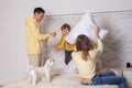Cute family, parents with adorable child son and white litte dog playing with pillows Royalty Free Stock Photo