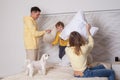 Cute family, parents with adorable child son and white litte dog playing with pillows