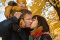 Cute family portrait. Man kissing woman in autumn park. Loving parents with son Royalty Free Stock Photo