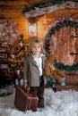 Cute fashion toddler boy, playing in the snow with teddy bear in front of a wooden cabin log Royalty Free Stock Photo