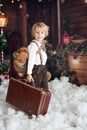 Cute fashion toddler boy, playing in the snow with teddy bear in front of a wooden cabin log Royalty Free Stock Photo