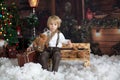 Cute fashion toddler boy, playing in the snow with teddy bear in front of a wooden cabin log Royalty Free Stock Photo