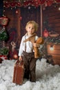 Cute fashion toddler boy, playing in the snow with teddy bear in front of a wooden cabin log Royalty Free Stock Photo