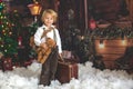 Cute fashion toddler boy, playing in the snow with teddy bear in front of a wooden cabin log Royalty Free Stock Photo