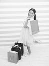 Cute fashionista. Child girl carries shopping bags striped bacground. In all ages women adore shopping. Girl smiling Royalty Free Stock Photo