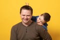 Cute father and son hugging on yellow background. Portrait of a dad with a baby boy smiling and hugging. Family concept Royalty Free Stock Photo