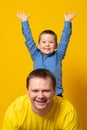 Cute father and son hugging on yellow background. Portrait of a dad with a baby boy smiling and hugging. Family concept Royalty Free Stock Photo