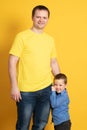 Cute father and son hugging on yellow background. Portrait of a dad with a baby boy smiling and hugging. Family concept Royalty Free Stock Photo