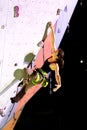 Cute female Athlete hanging on climbing Wall