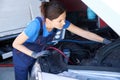 Cute female auto mechanic in work overalls works