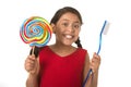 Cute female child holding big spiral lollipop candy and huge toothbrush in dental care concept Royalty Free Stock Photo