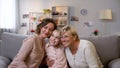 Cute female family embracing, sitting on sofa at home, trustful relationship