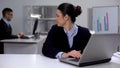 Cute female manager working on laptop, looking at male colleague, secret love Royalty Free Stock Photo