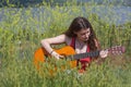 Cute female Musician sitting on green Grass