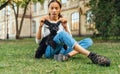 Cute female owner playing with a cute funny dog peeking on the lawn on the street, lifts the pet`s ears up and smiles