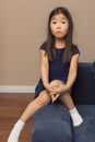 Cute female portrait of little surprised girl, pretty adorable asian relaxed child surprising on blue couch at home