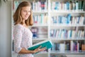 Cute female student with books in library Royalty Free Stock Photo