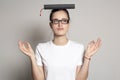 Cute female student woman with glasses meditating, she put the book on his head like a graduate cap and dreamily looks away. Royalty Free Stock Photo