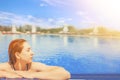 Woman looks out of the pool, hanging on railing. Royalty Free Stock Photo