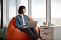 Cute female worker with portable laptop looking at window