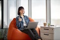 Cute female worker with portable laptop looking at window