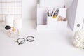 Cute feminine stuff on white table with glasses and flower, office background,