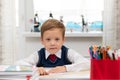 A cute first-grader boy in a school uniform at home while isolated at his desk makes a paper airplane during recess Royalty Free Stock Photo