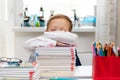 A cute first grader boy in a school uniform at home during a pandemic fell asleep doing homework at a desk with books and pencils