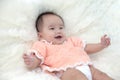 Cute five months asian baby in orange dress laughing