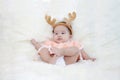 Cute five months asian baby in reindeer horns., on bright soft carpet